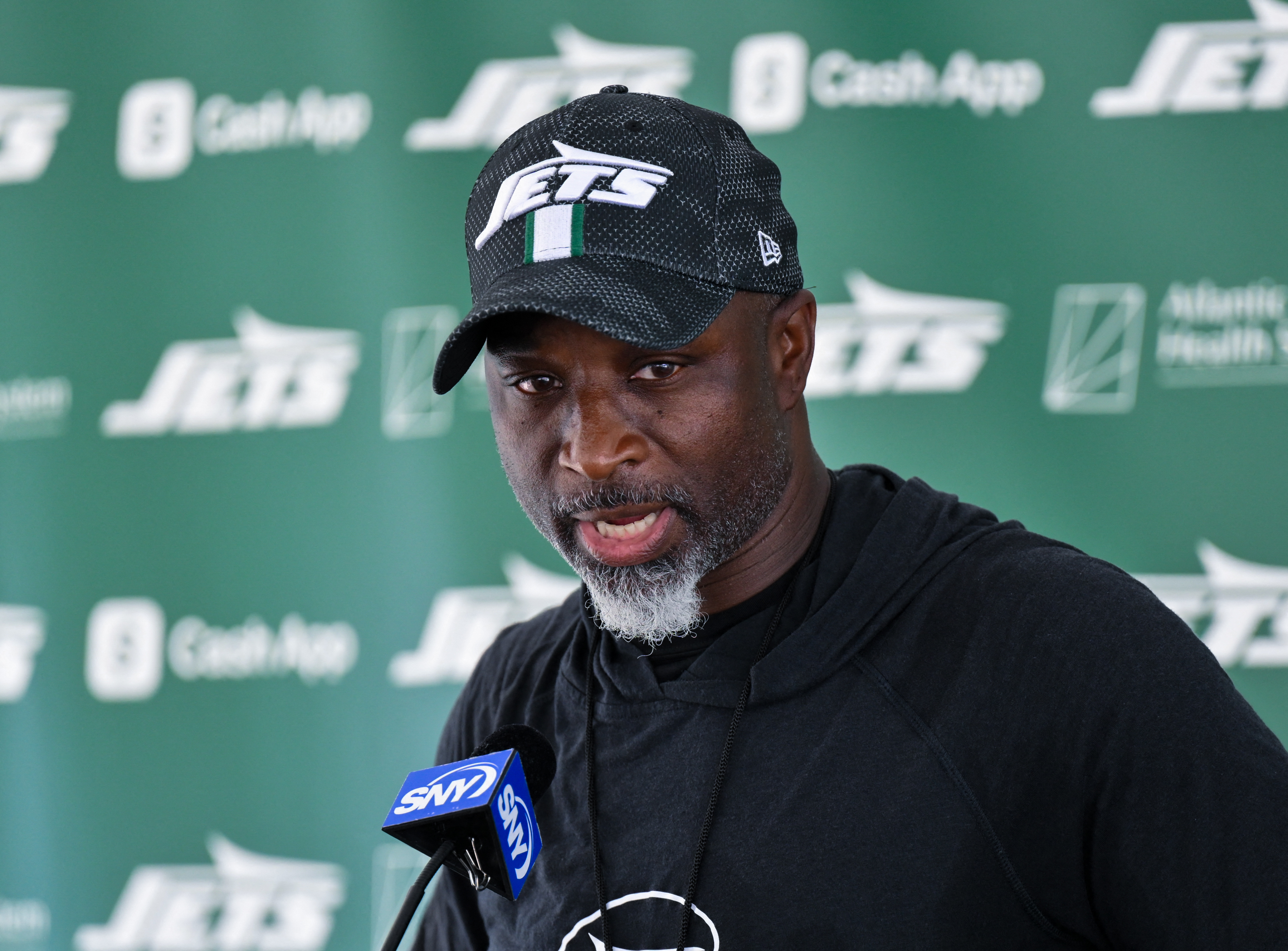 2025 Jets season preview: Justin Fields, the run game, 5 things to watch 3 man in Jets cap and shirt against green backdrop speaks into microphone