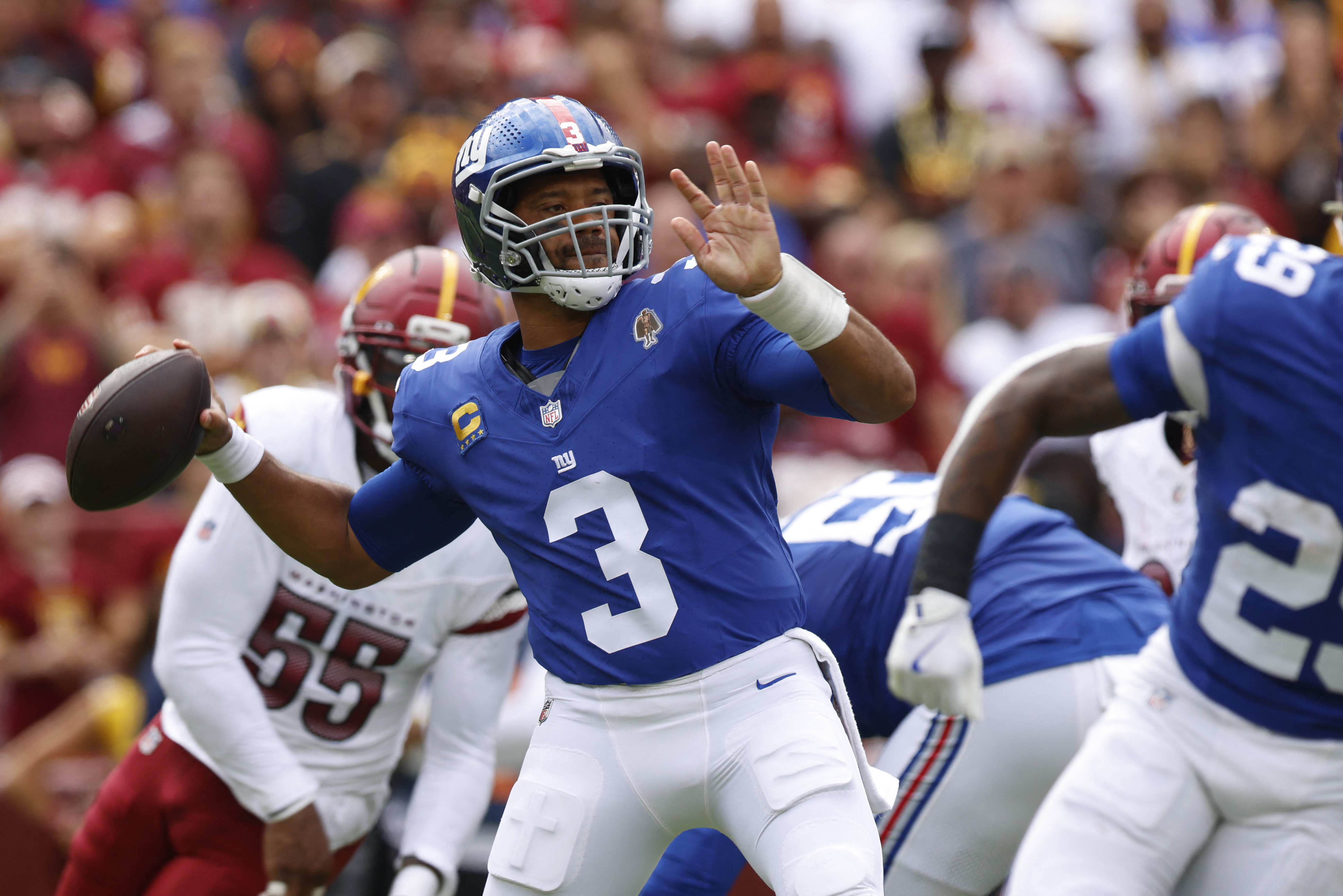 Russell Wilson Giants: Man in blue football uniform and helmet throws ball