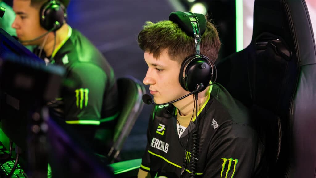 Image of Mercules wearing an OpTic Texas jersey at a Call of Duty League event. Mercules is wearing a headset while Shotzzy is in the background looking at a PC monitor.